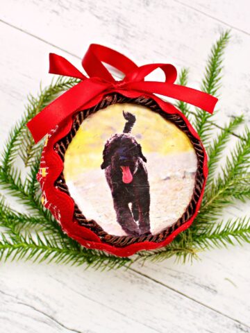 close up of round fabric ornament with trim and ribbon attached