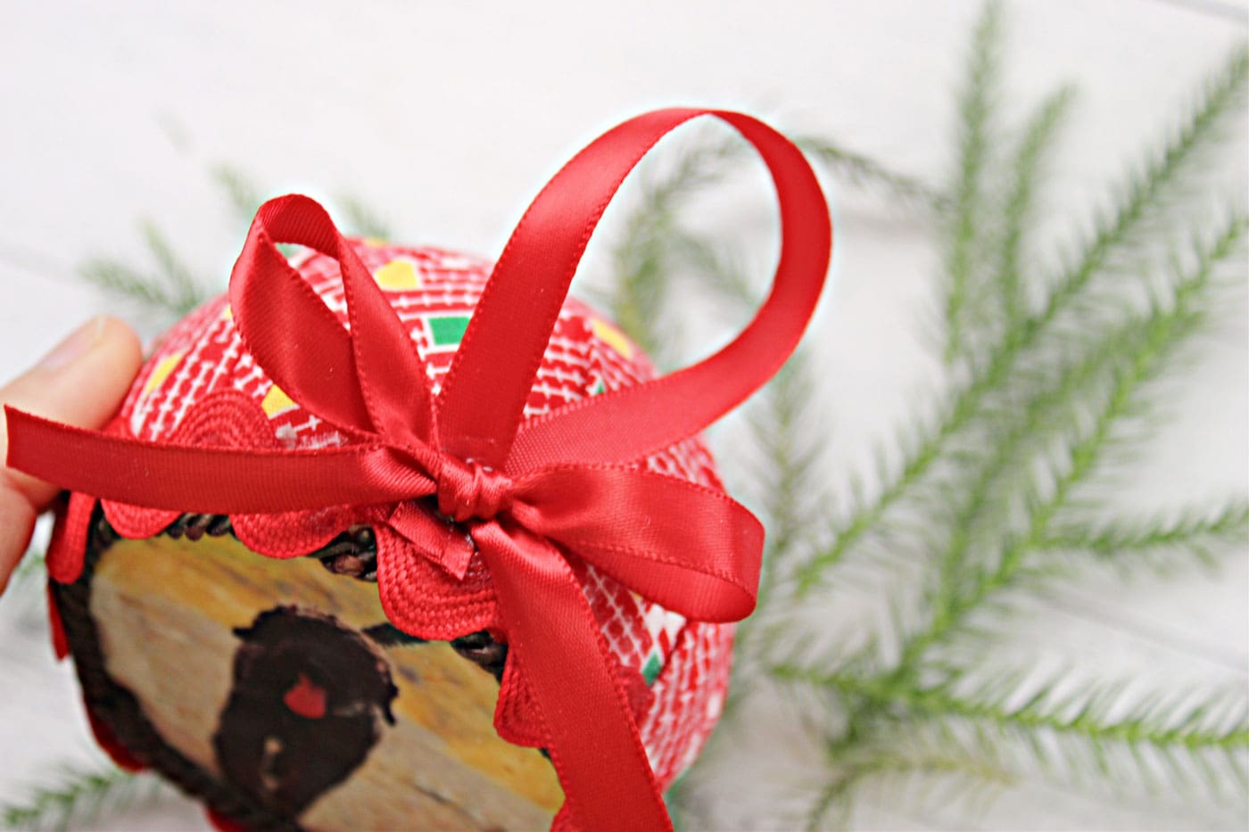 close up of round fabric ornament with trim and ribbon attached