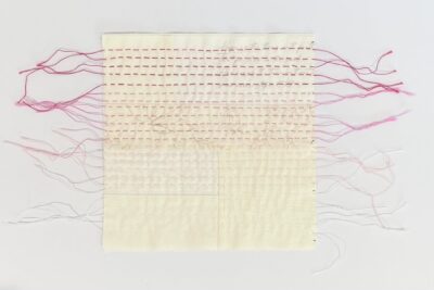 close up of cream fabrics stitched together on white table with pink hand stitching and needle