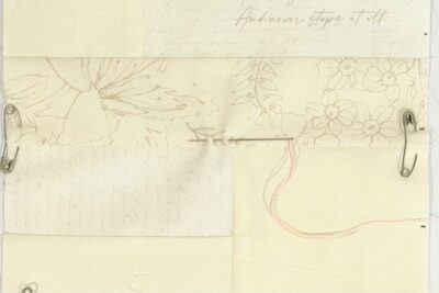 close up of cream fabrics stitched together on white table with pink hand stitching and needle
