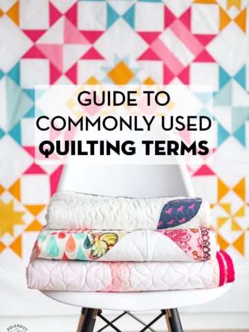 white chair with quilts stacked ontop in front of a colorful geometric quilt with text overlay