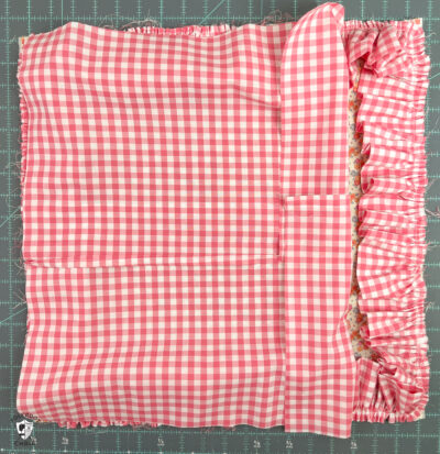 pink gingham fabric on top of ruffled pillow