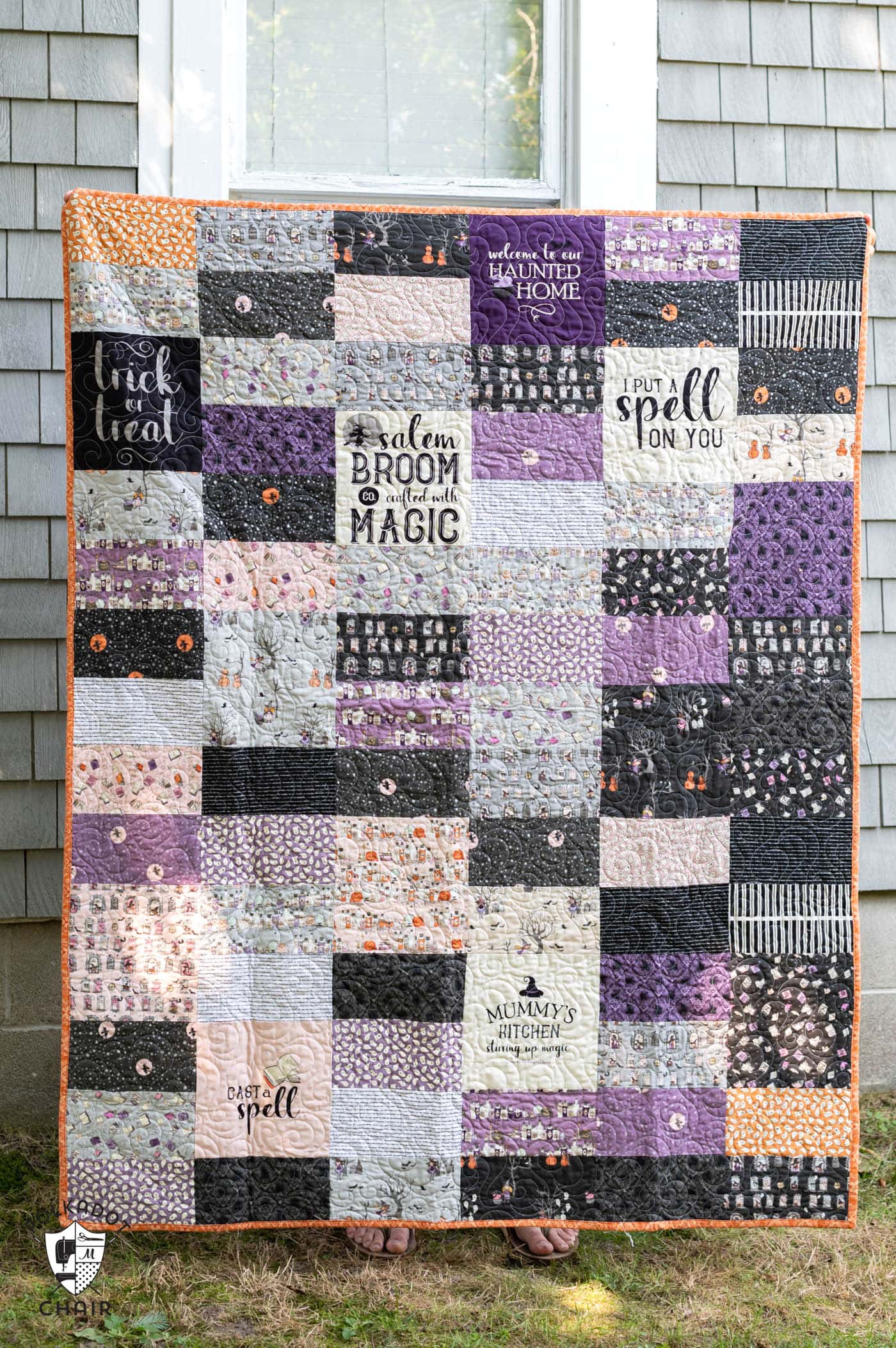 Purple ivory and gray Halloween quilt in front of gray house