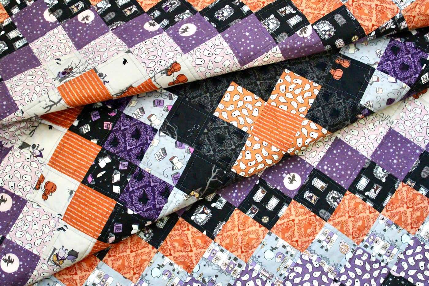 close up of black, orange and purple patchwork quilt outdoors
