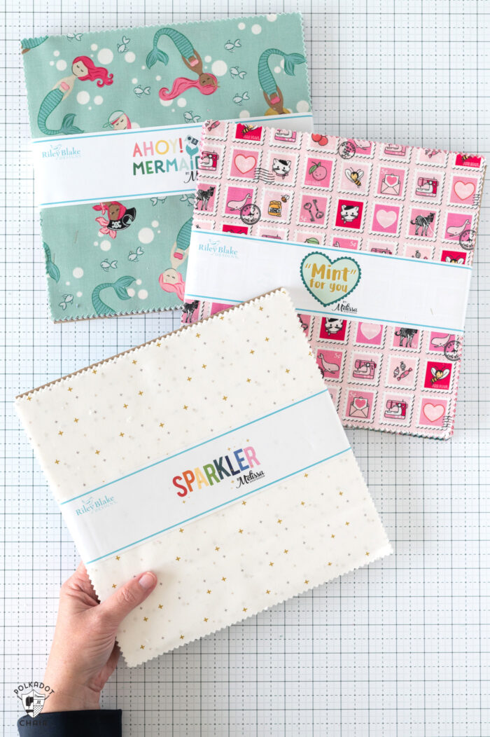 hand holding stack of fabric on cutting table