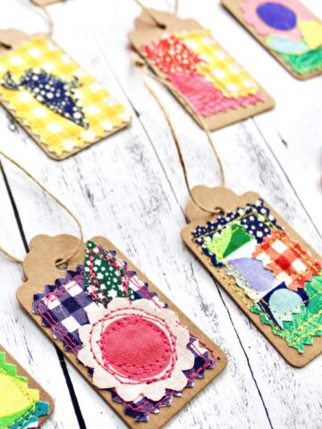 colorful fabric and paper gift tags on white wood table