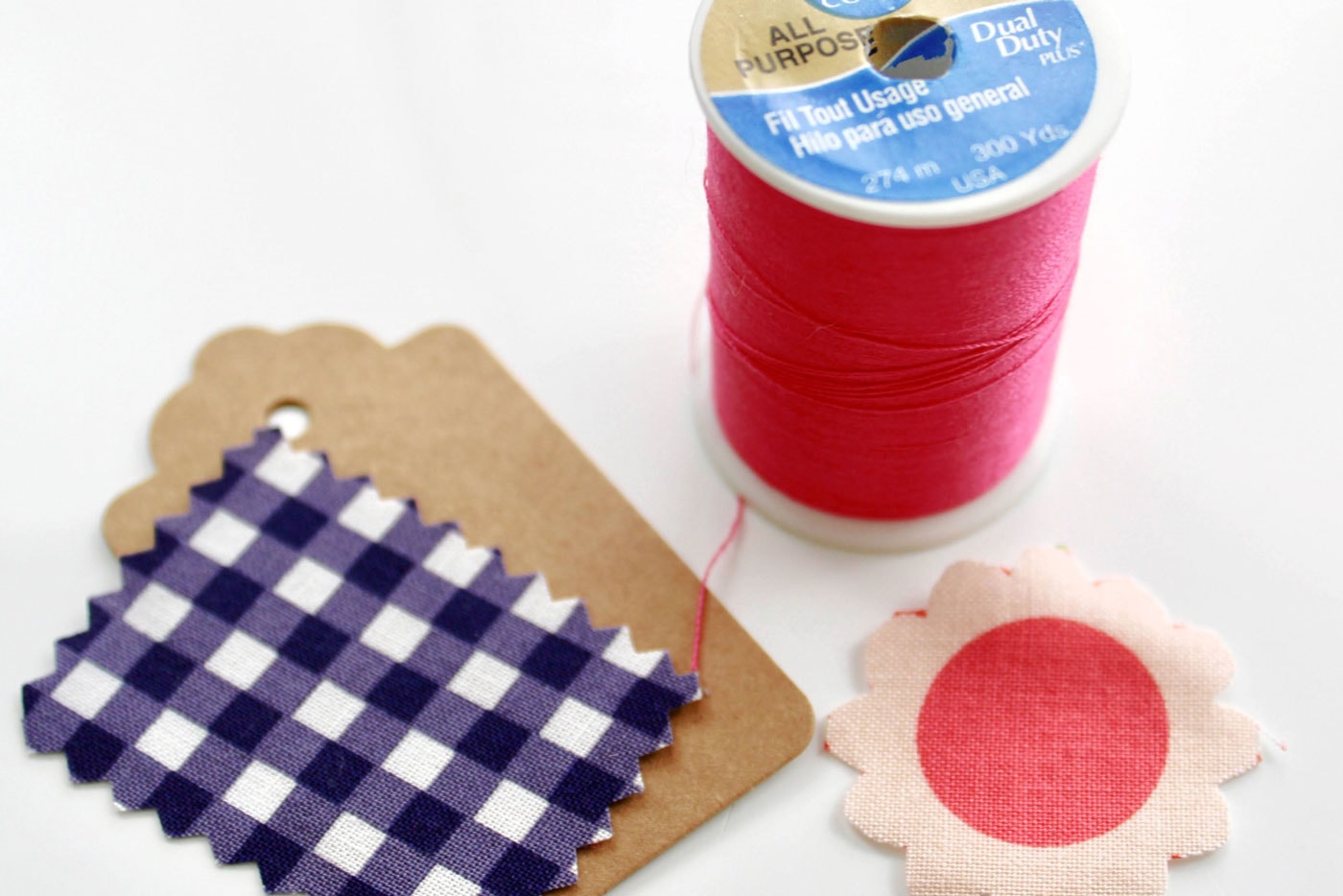 fabric scraps on white wood table with spool of pink thread