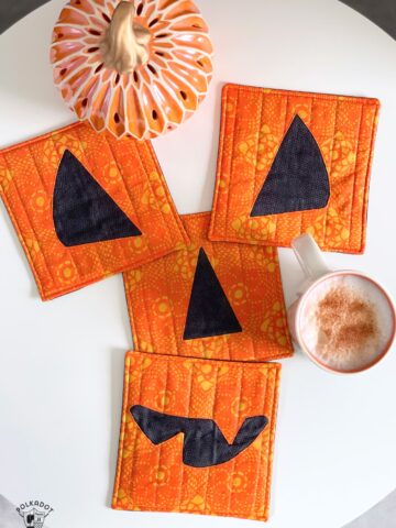 pumpkin face mug rug on white table with coffee cups