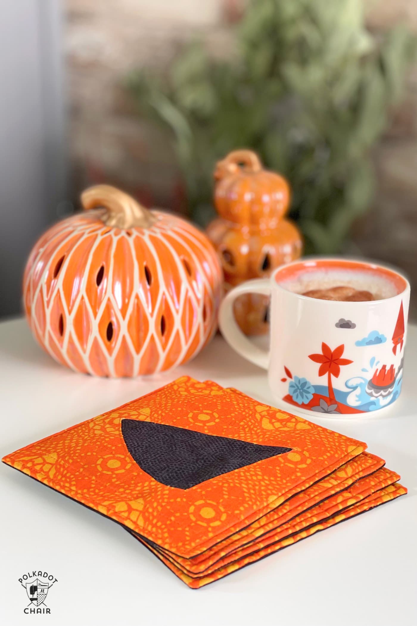 Pumpkin face mug mat on white table with coffee cups