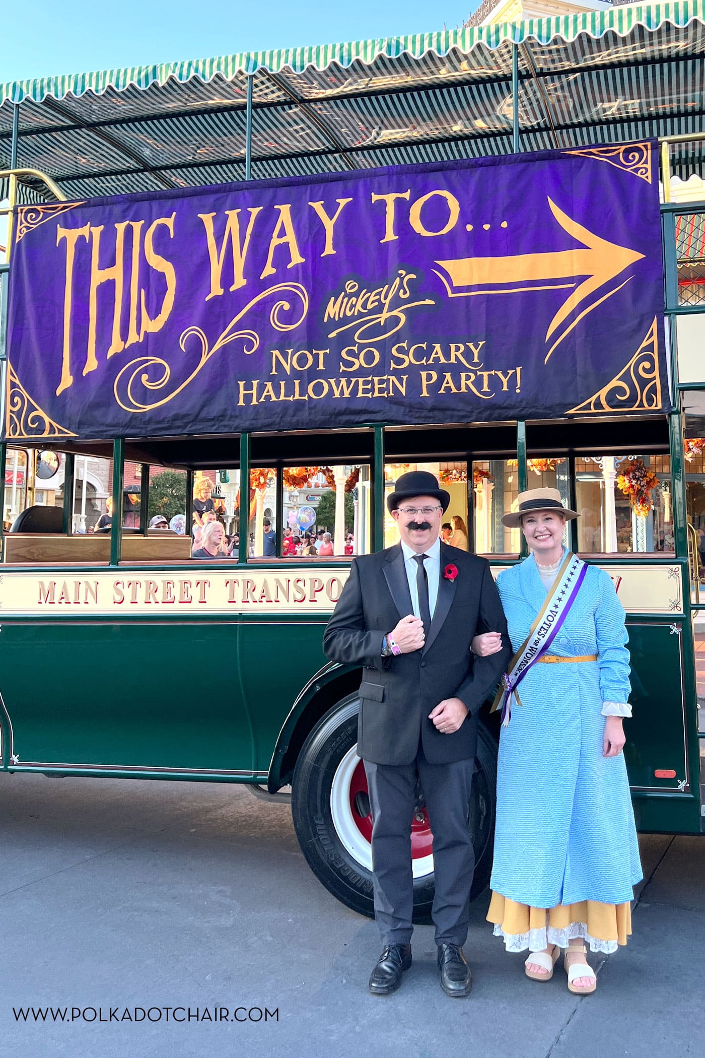 couple in costumes in front of sign at disneyworld