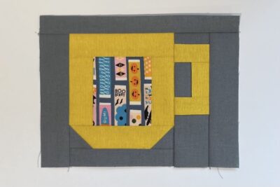 yellow cup quilt block with gray fabric on table