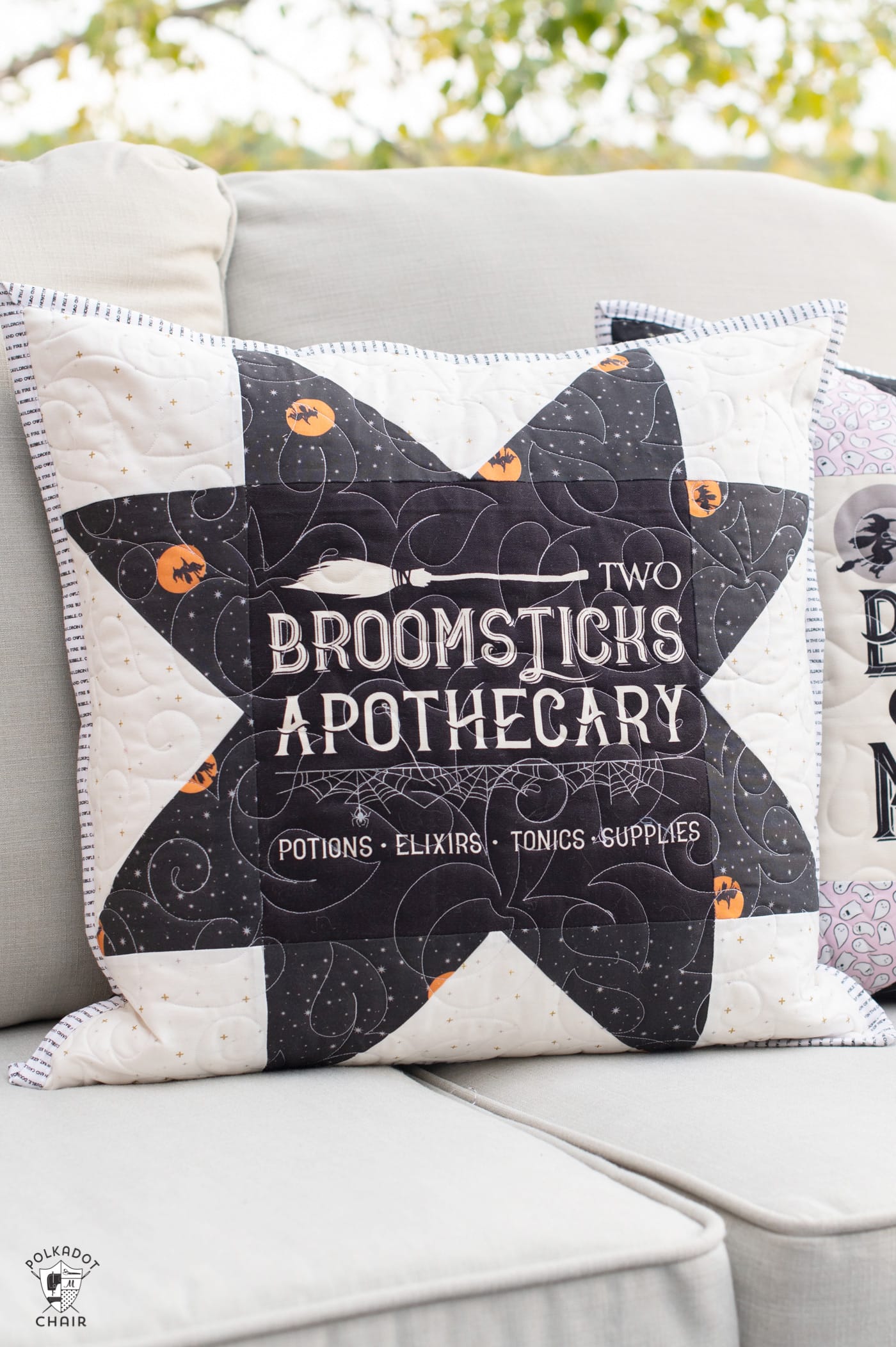 two black and white pillows on a couch outside with a Halloween quilt