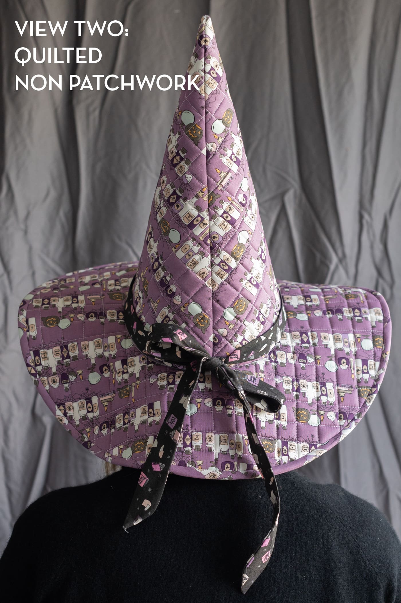 woman wearing patchwork witch hat in front of gray wall