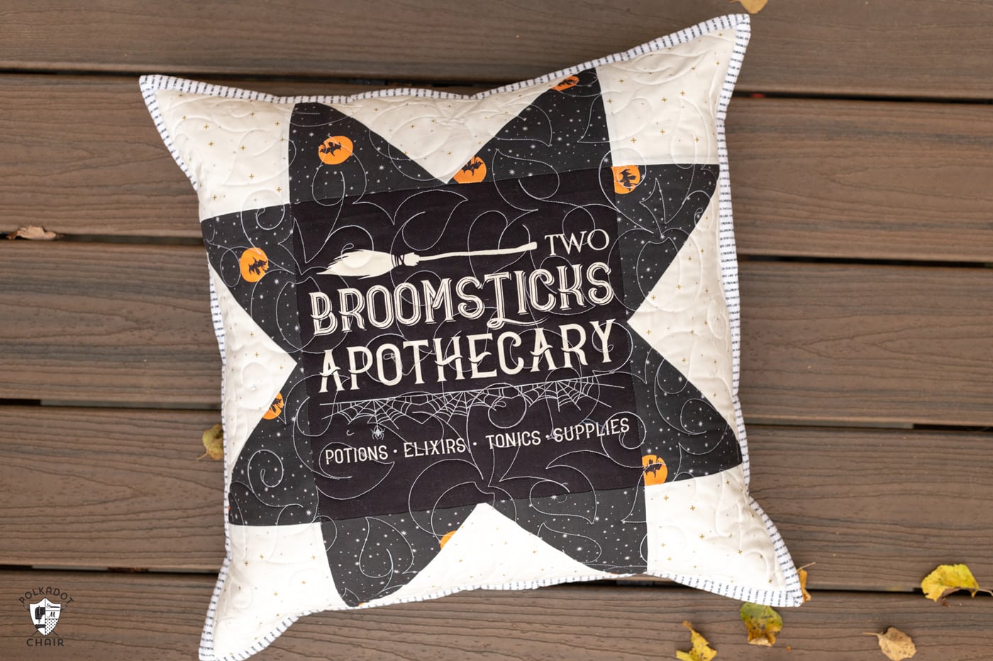 two black and white pillows on deck outdoors with halloween quilt