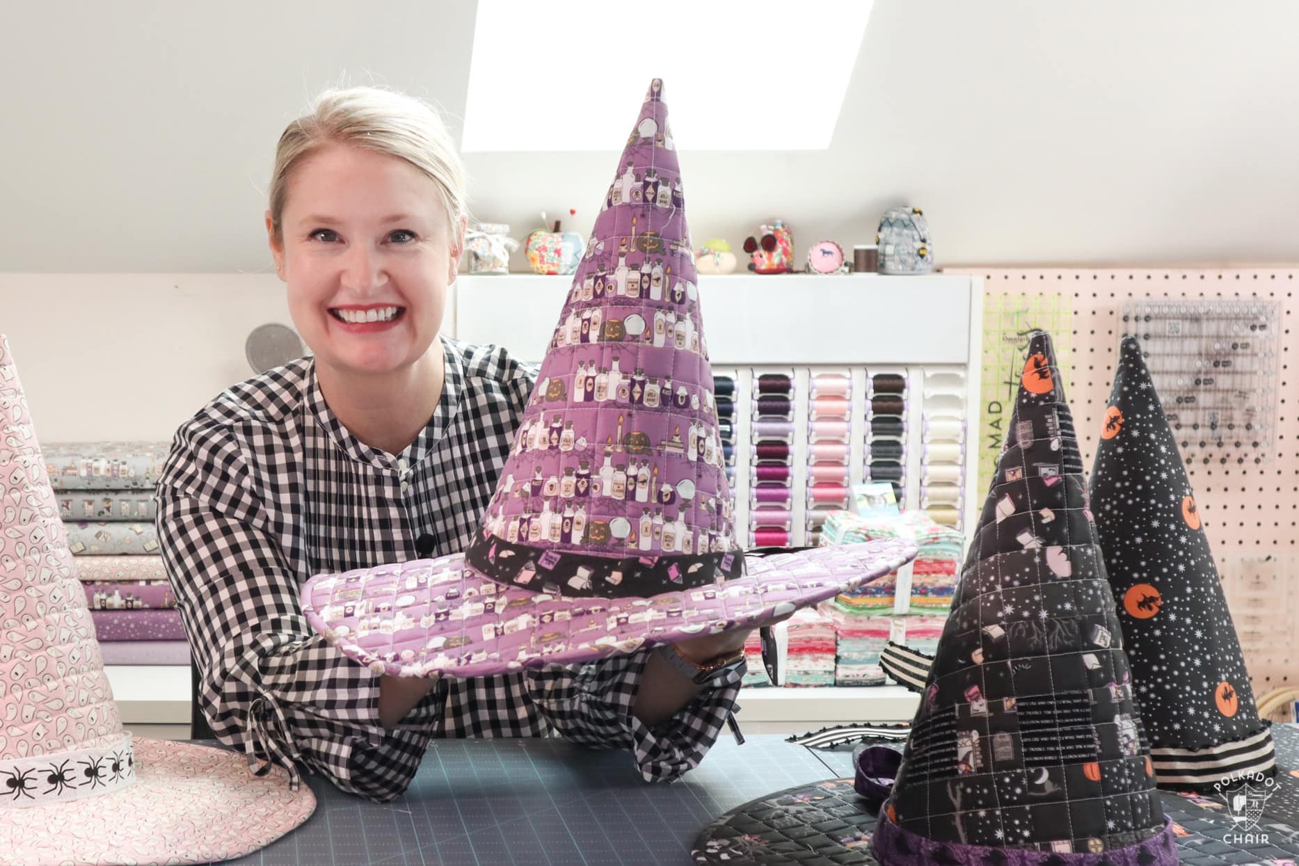 woman holding witch hat in front of sewing machine