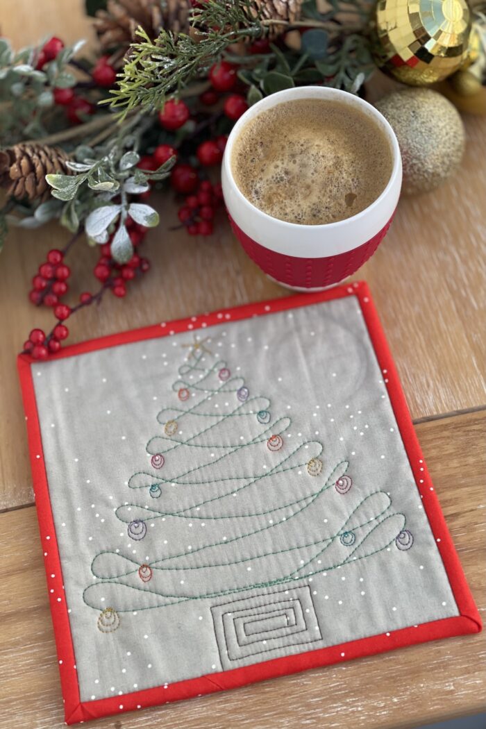 gray and red mug rug on wood table with coffee cup and christmas decorations