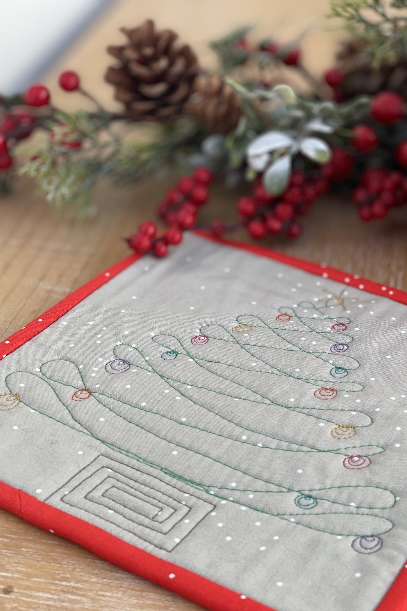 gray and red mug rug on wood table with coffee cup and christmas decorations