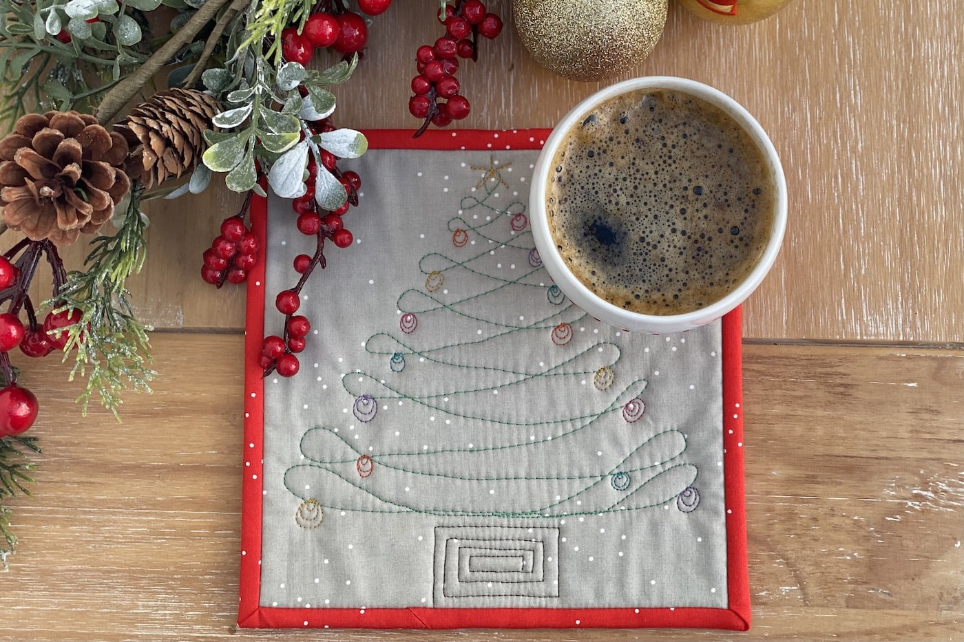 gray and red mug rug on wood table with coffee cup and christmas decorations