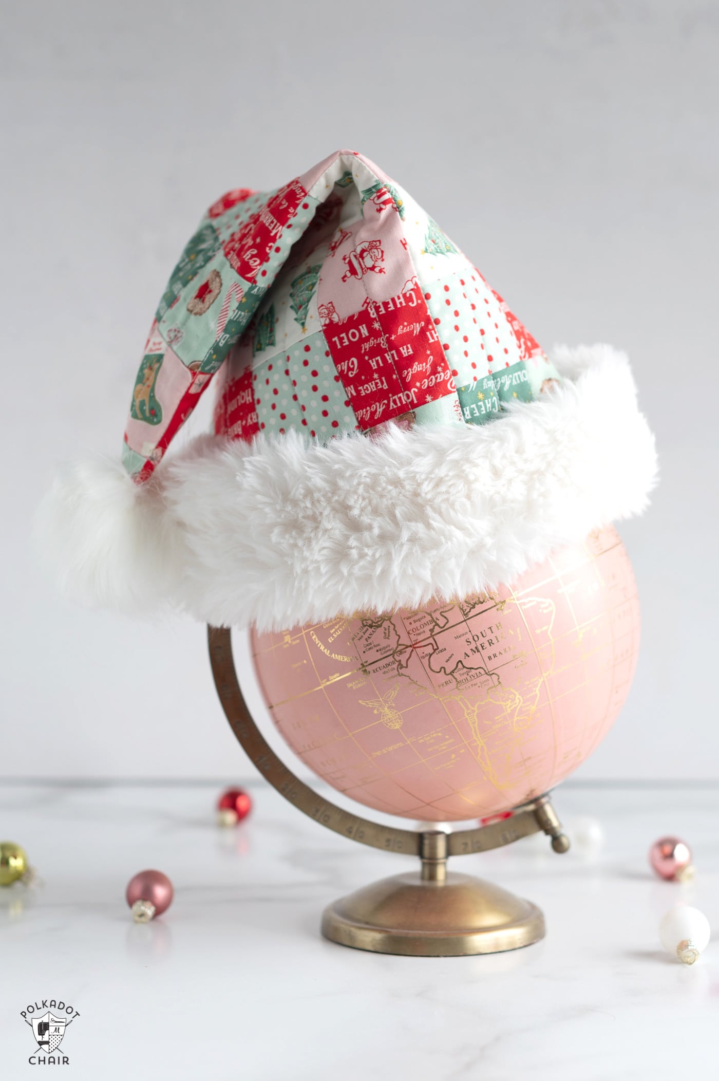 Red, pink and green patchwork santa hat on pink globe