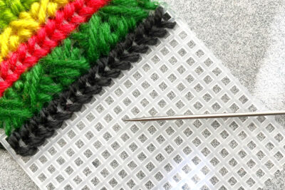 plastic canvas construction steps in detail with yarn, needles on white table