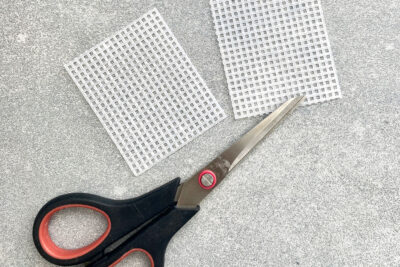 plastic canvas construction steps in detail with yarn, needles on white table