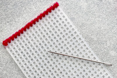 plastic canvas construction steps in detail with yarn, needles on white table