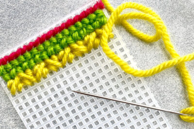 plastic canvas construction steps in detail with yarn, needles on white table