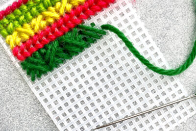 plastic canvas construction steps in detail with yarn, needles on white table