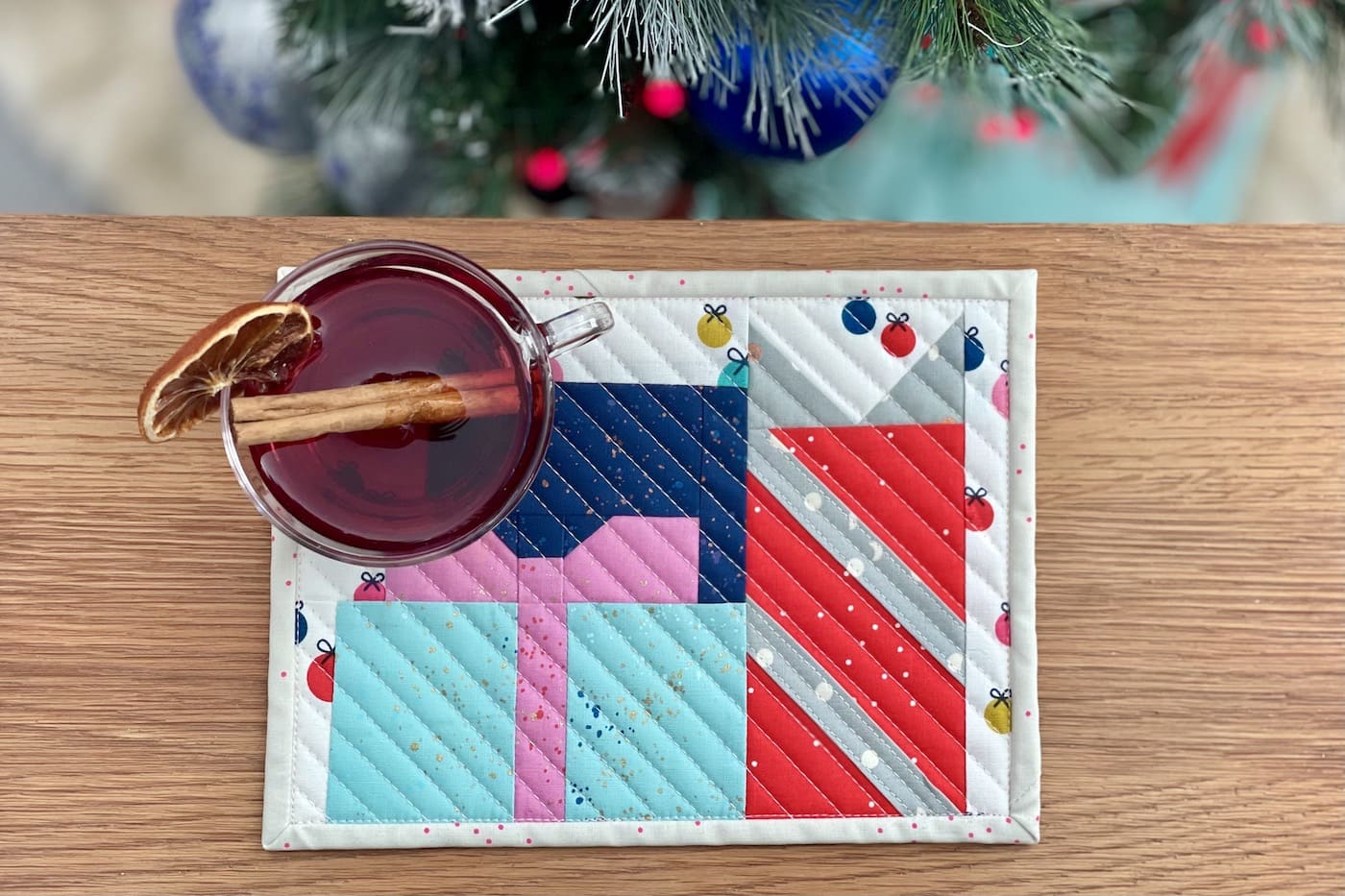 colorful presents mug rug on wood table in front of Christmas tree