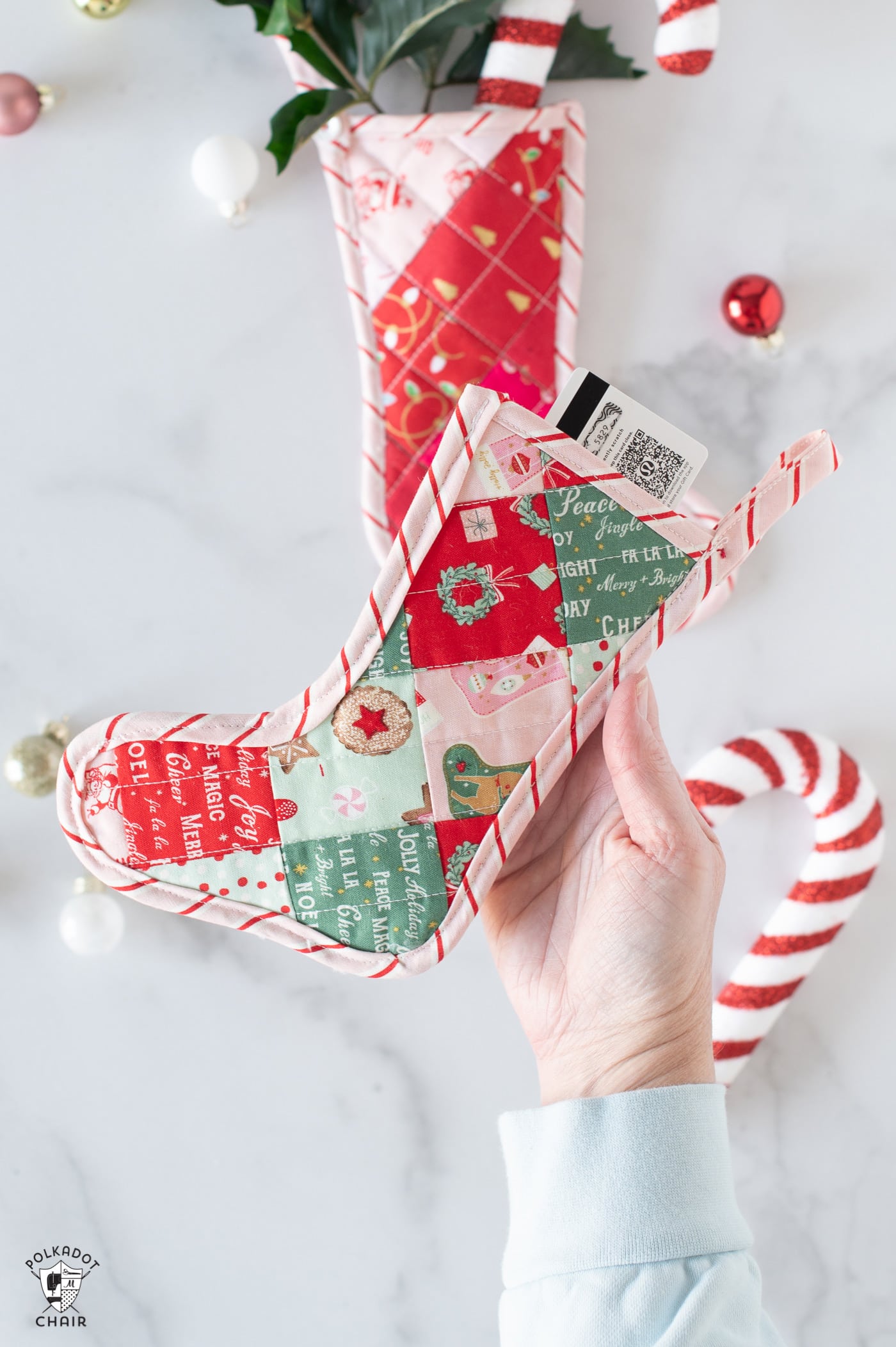 Pink and red mini quilted stockings on white tabletop with Christmas decorations