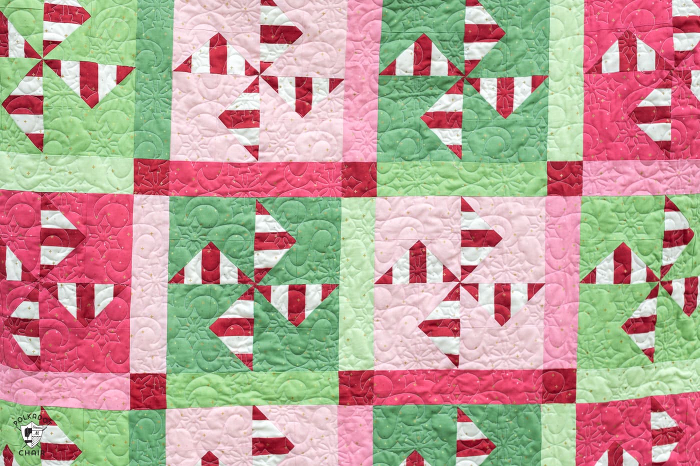 woman holding red, white, pink and green christmas quilt outdoors