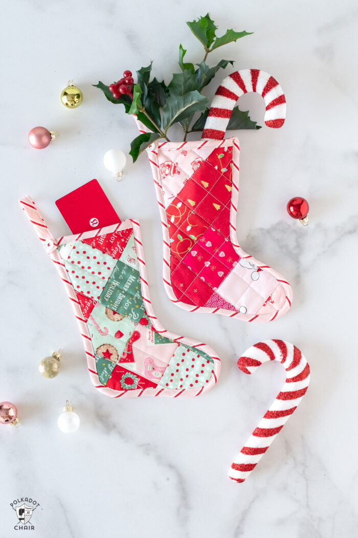 Pink and red mini quilted stockings on white tabletop with Christmas decorations