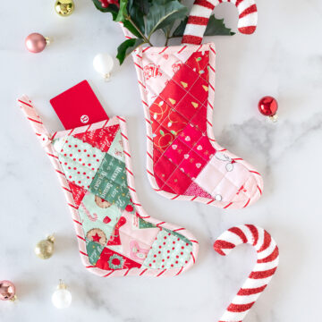 Pink and red mini quilted stockings on white tabletop with Christmas decorations