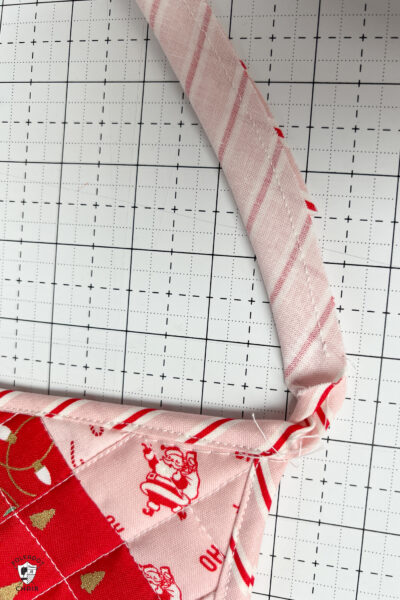 pink and red Christmas stocking in construction process on white cutting mat