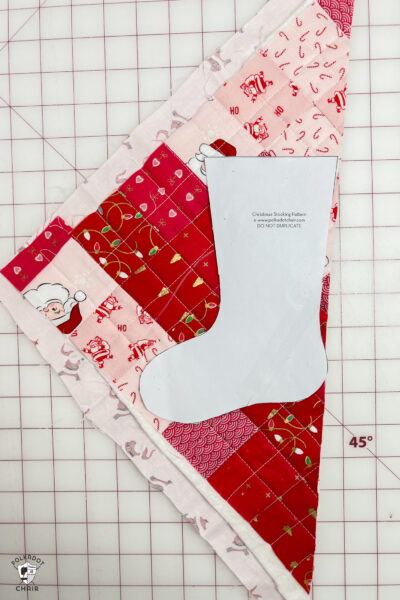 pink and red Christmas stocking in construction process on white cutting mat