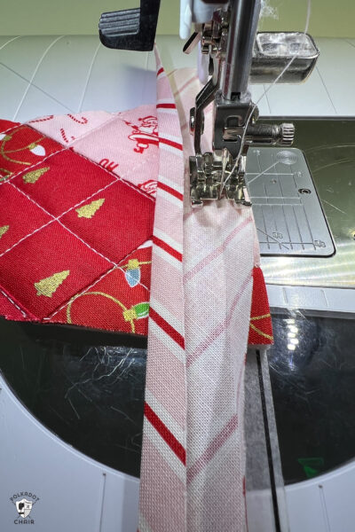 pink and red Christmas stocking in construction process on white cutting mat