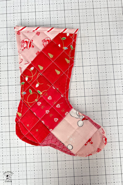 pink and red Christmas stocking in construction process on white cutting mat