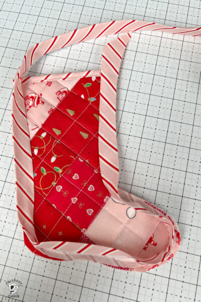 pink and red Christmas stocking in construction process on white cutting mat