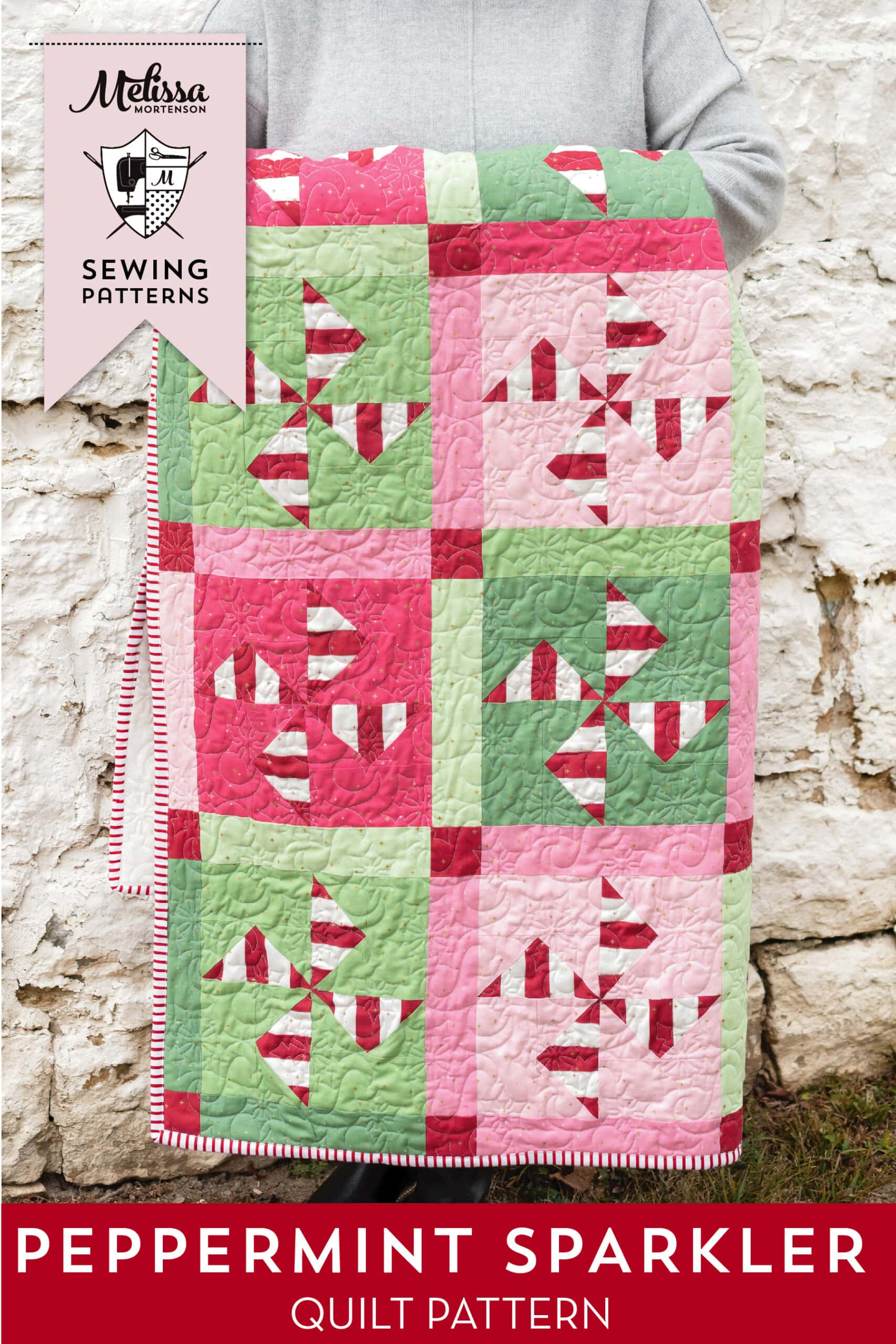 woman holding red, white, pink and green christmas quilt outdoors