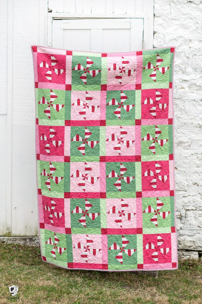 woman holding red, white, pink and green christmas quilt outdoors