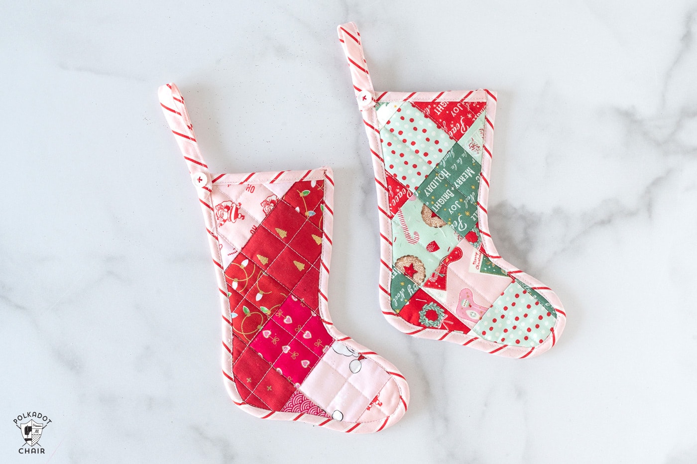 Pink and red mini quilted stockings on white tabletop with Christmas decorations