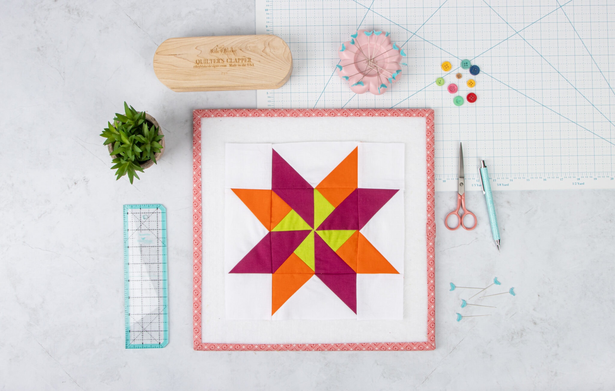 orange, purple and green quilt blocks on a white table with sewing notions