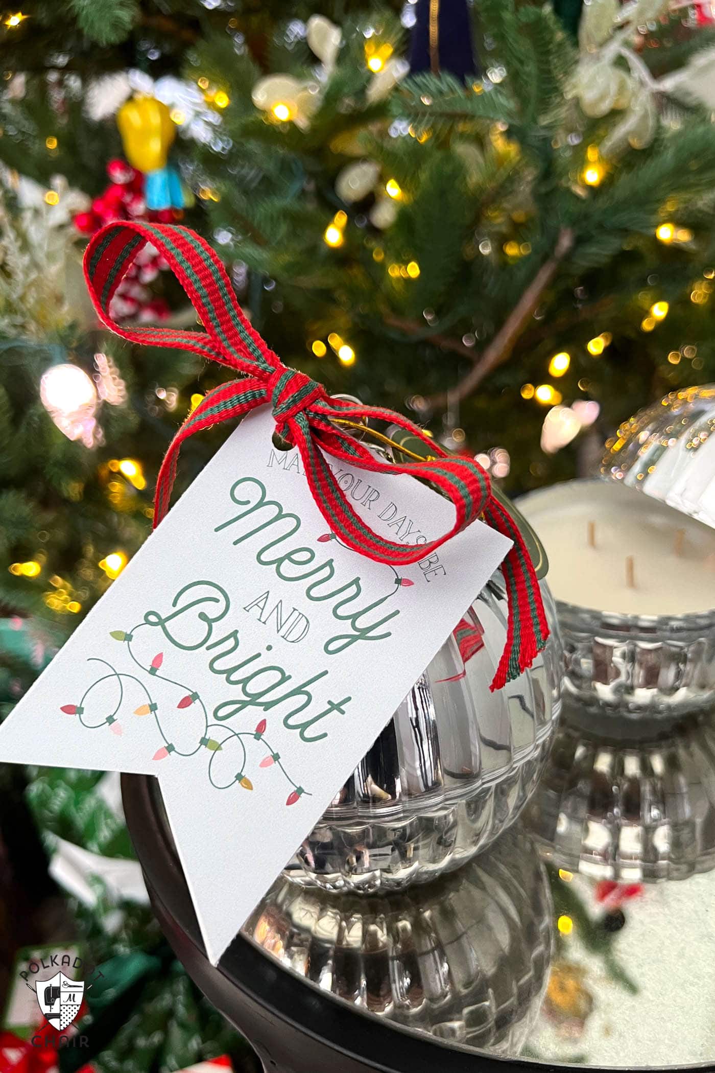 gift tag tied to round candle in front of Christmas tree