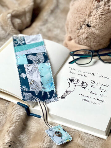 Blue patchwork bookmark on book on tan blanket