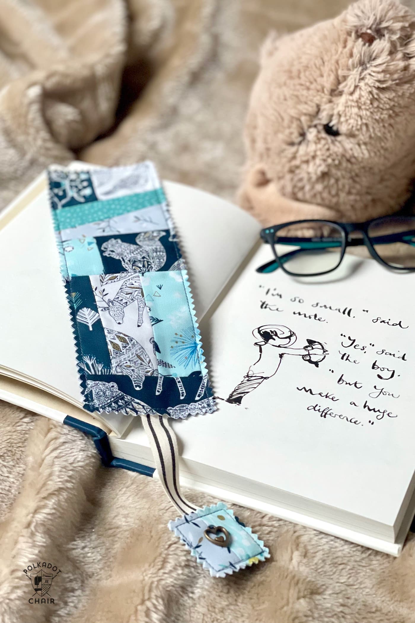 Blue patchwork bookmark on book on tan blanket