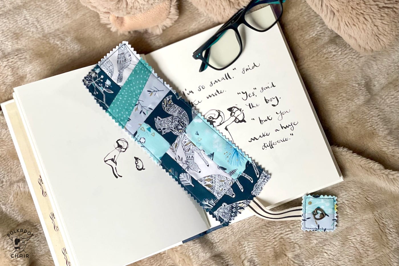 Blue patchwork bookmark on book on tan blanket