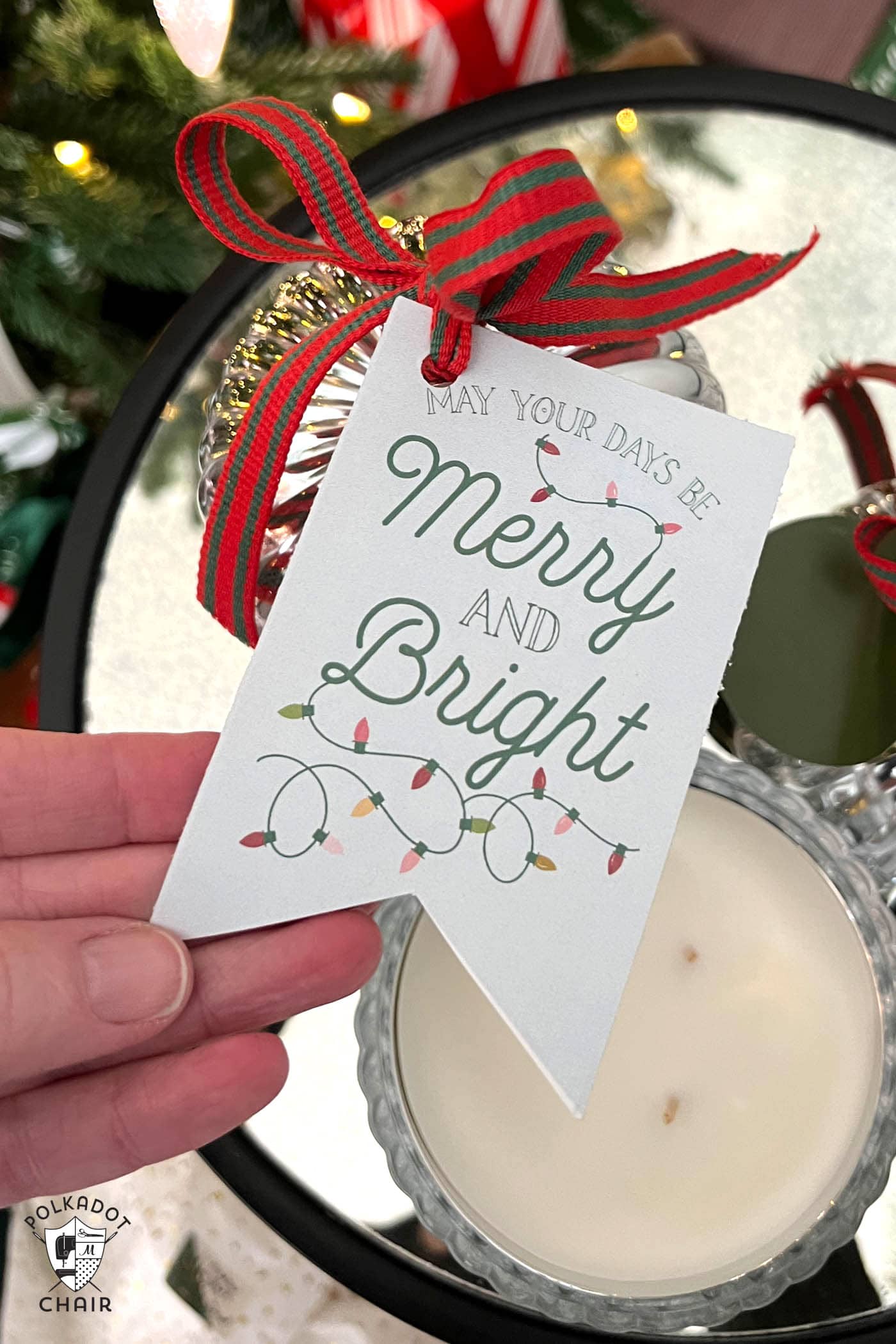 gift tag tied to round candle in front of Christmas tree