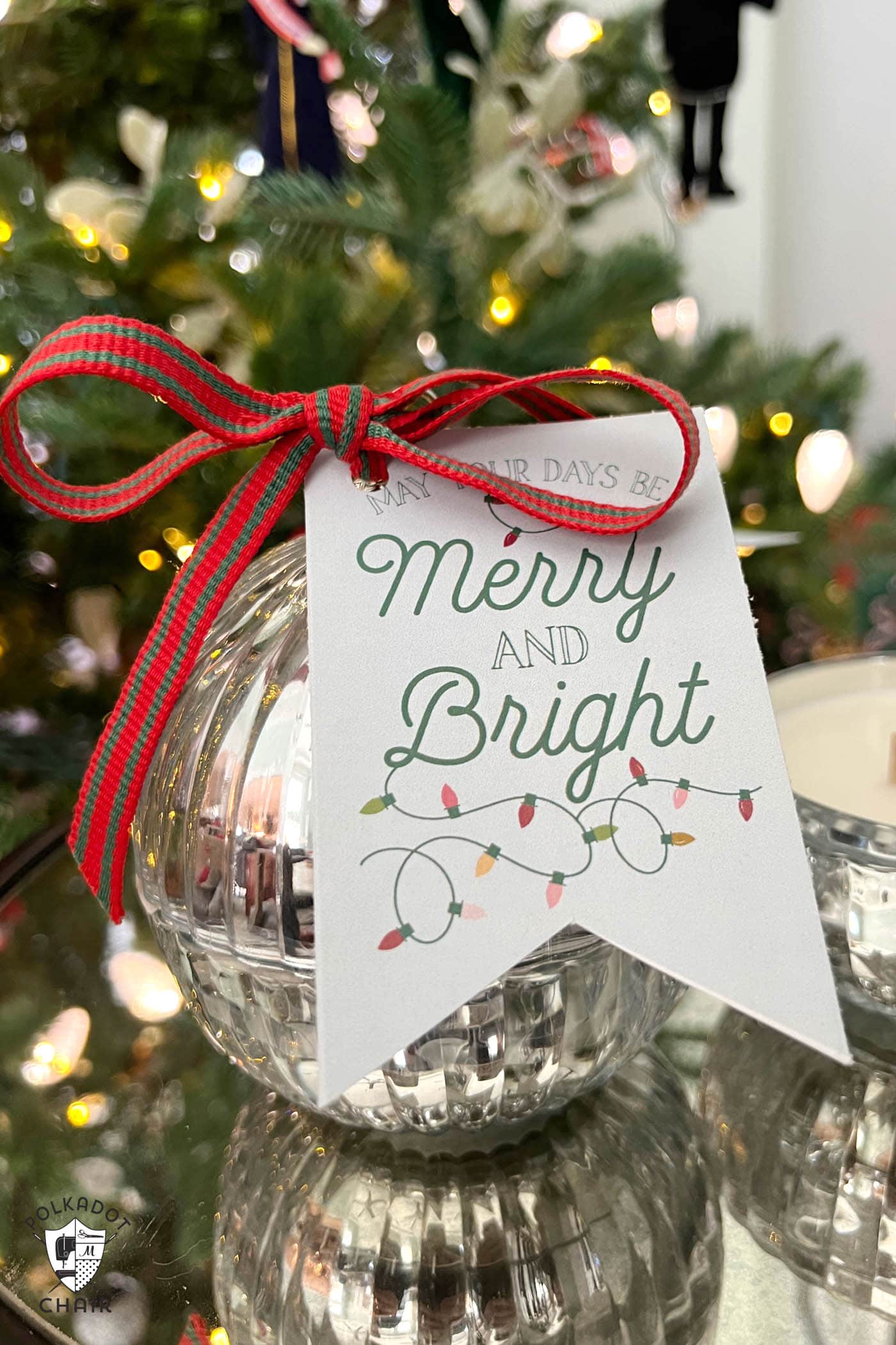 gift tag tied to round candle in front of Christmas tree