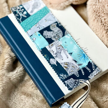 Blue patchwork bookmark on book on tan blanket