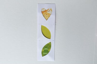 yellow and green fabrics on white table with white paper cut outs